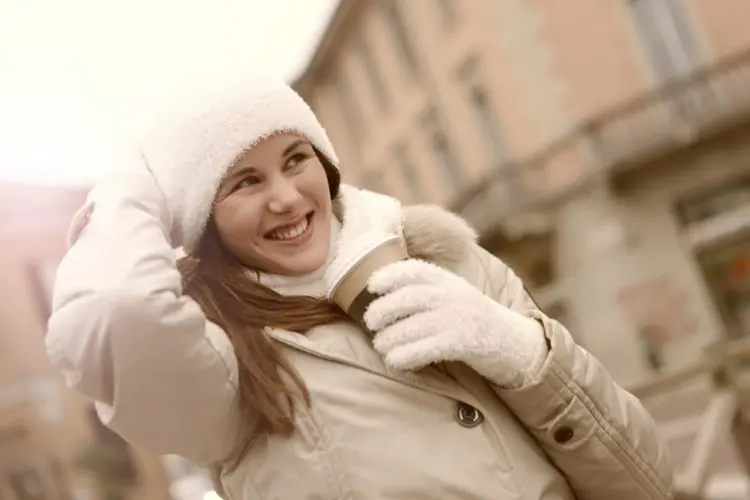 winter mouth care tips -- woman wearing gloves, scarf and hat holding a hot drink