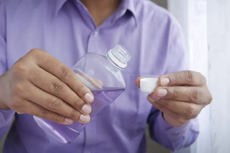 is mouthwash effective -- man pouring mouthwash into a cup