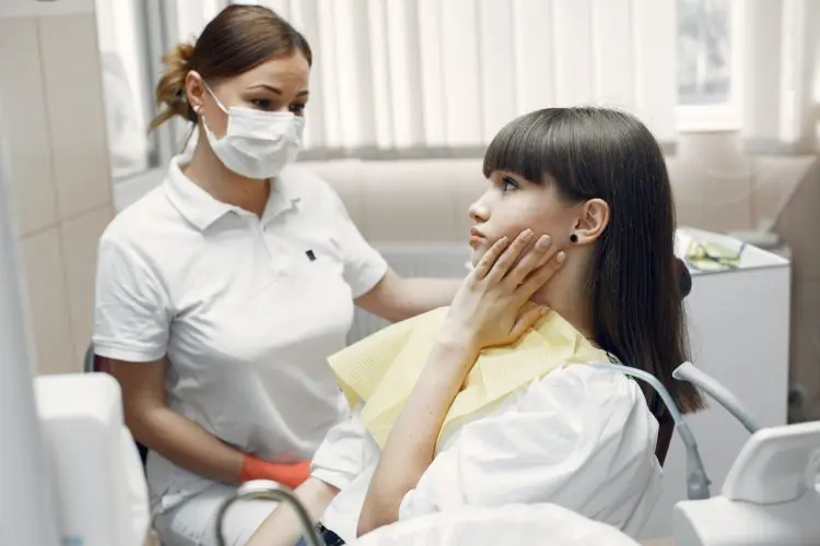 effects of teeth grinding - woman with toothache in dental office