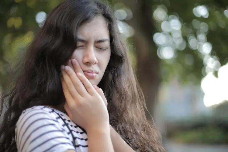 what's causing my tooth pain - woman holding jaw in pain