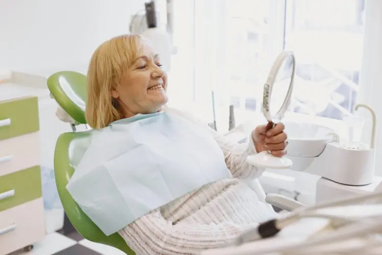 senior woman smiling looking at mirror in dentist chair