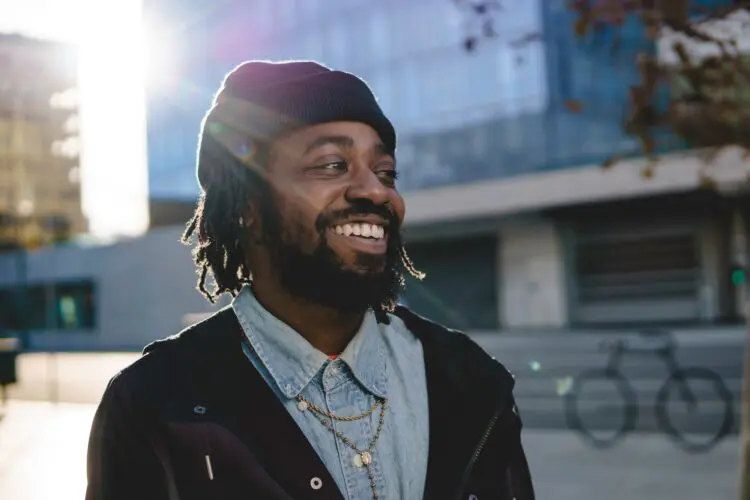 man walking down sunny street and smiling