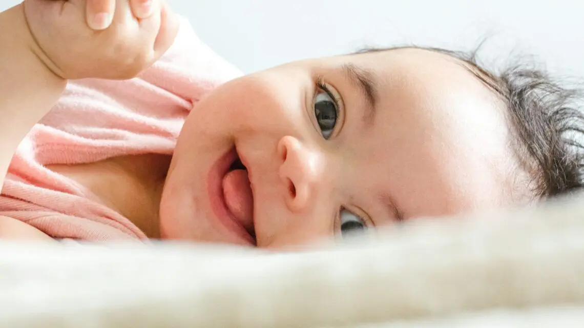 baby laying down with big smile - brushing baby teeth