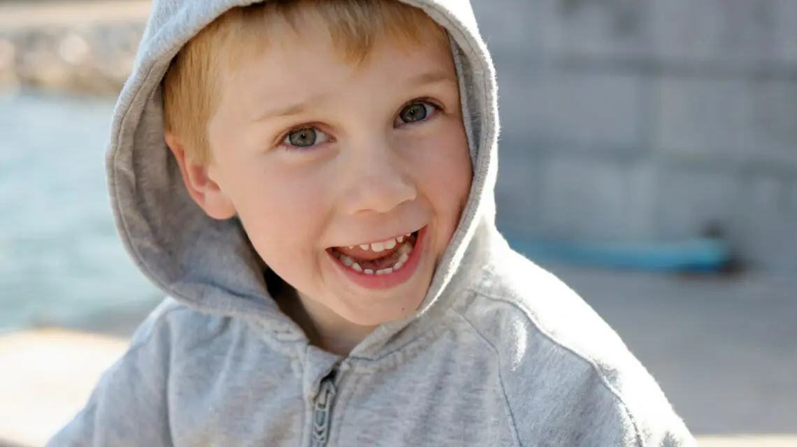 boy in grey hoodie with big smile