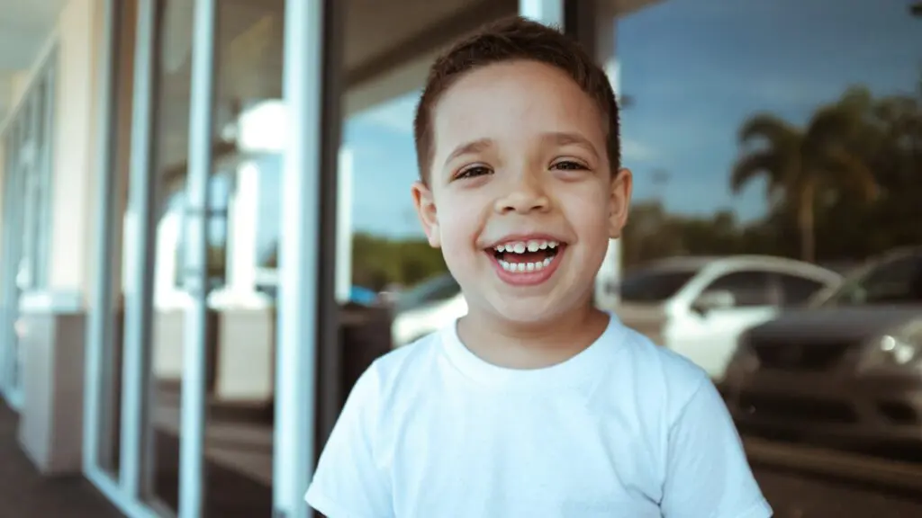 child in a white shirt with big smile.