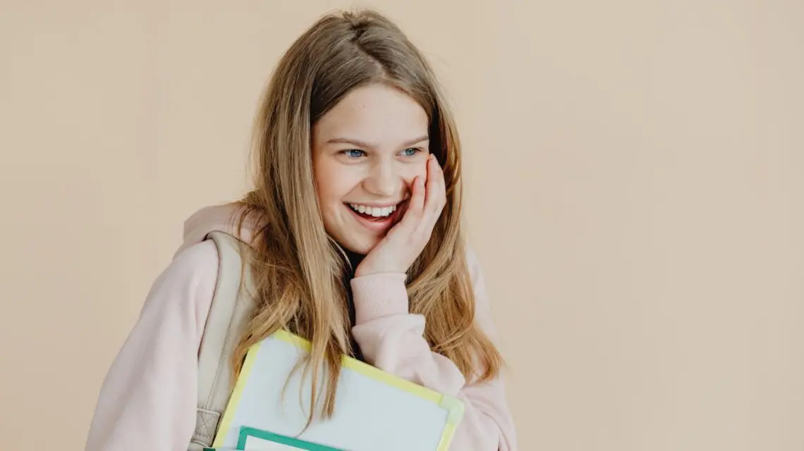 teenager smiling carrying school books and backpack
