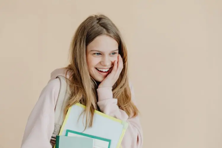 teenager smiling carrying school books and backpack