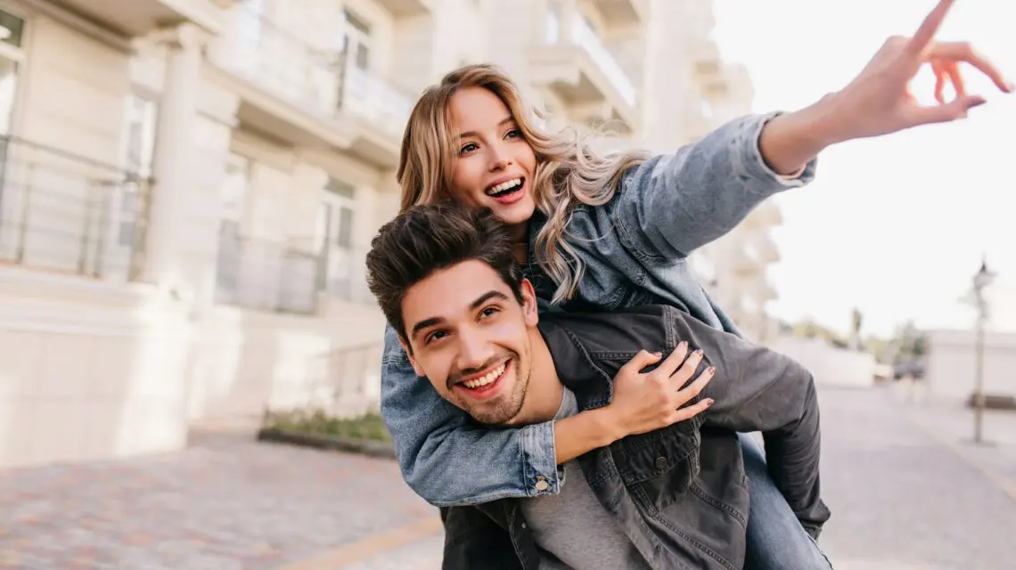 couple smiling walking with the woman on the man's back