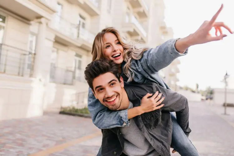 couple smiling walking with the woman on the man's back