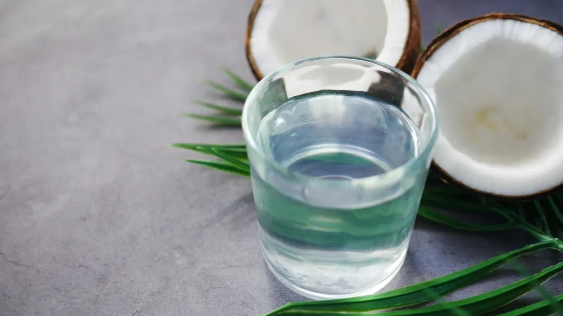 cut open coconut next to glass of water