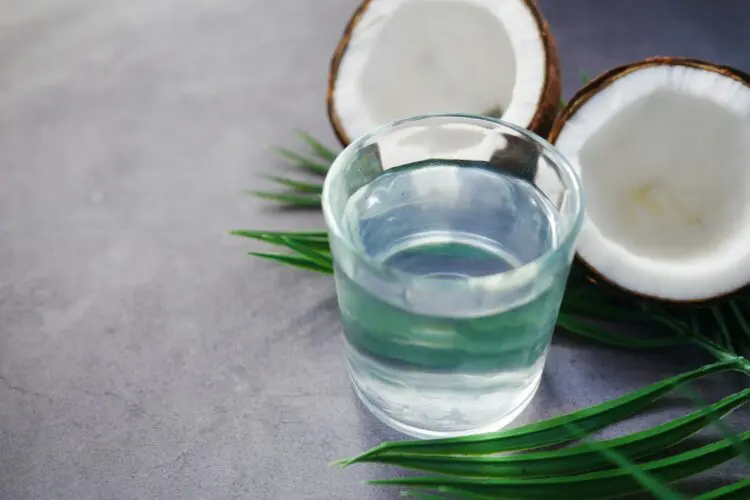cut open coconut next to glass of water