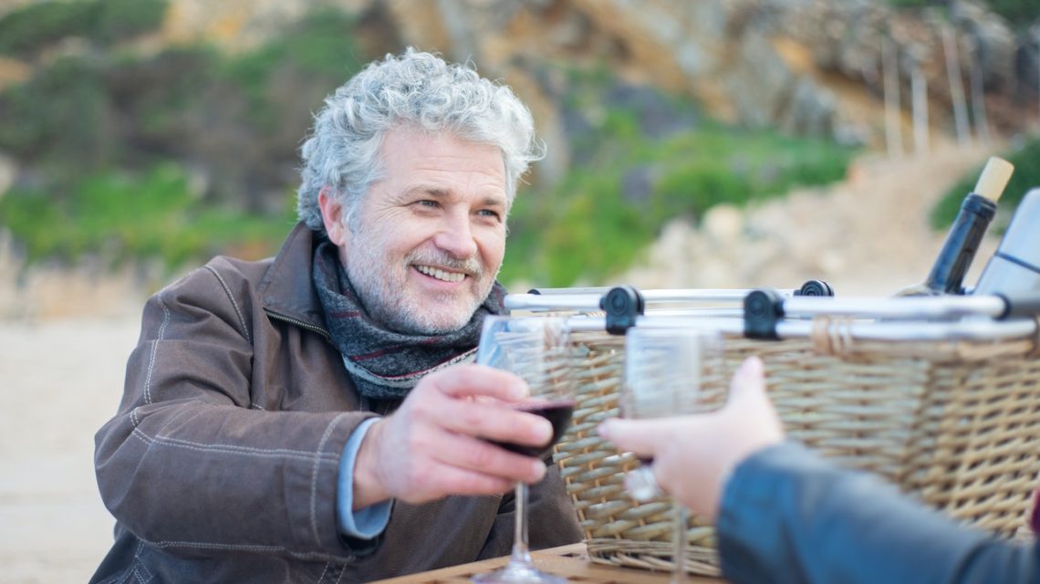 how to clean dentures -- older man holding a wine glass and smiling