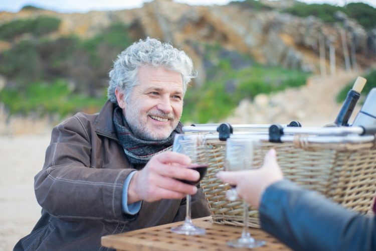 how to clean dentures -- older man holding a wine glass and smiling