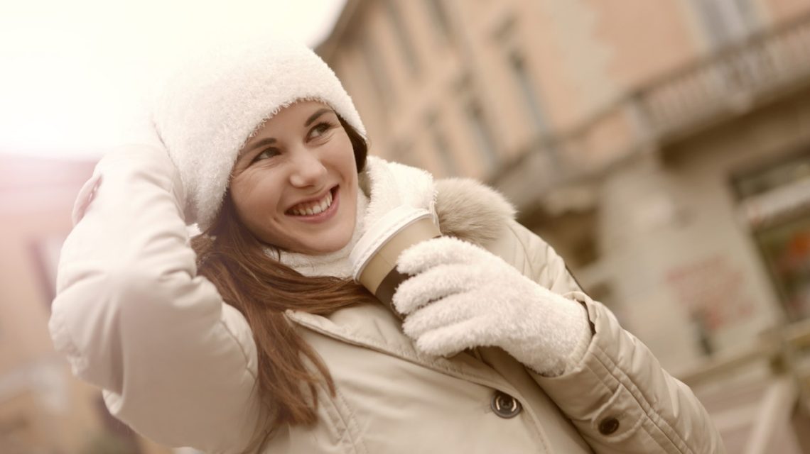 winter mouth care tips -- woman wearing gloves, scarf and hat holding a hot drink
