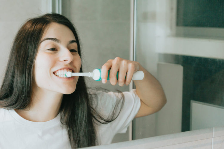 woman brushes teeth in a mirror