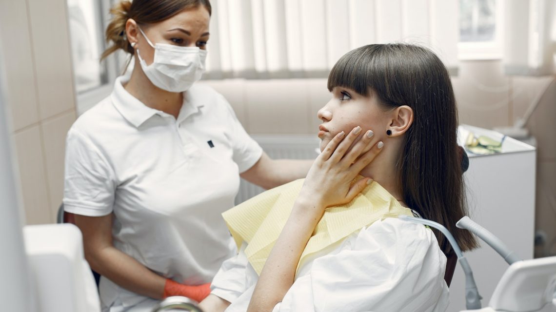 effects of teeth grinding - woman with toothache in dental office