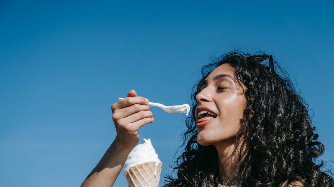 woman eating ice cream cone blue background