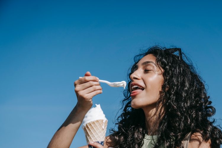 woman eating ice cream cone blue background