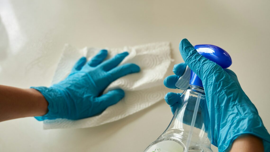 blue gloved hands holding cleaning products - dental infection control