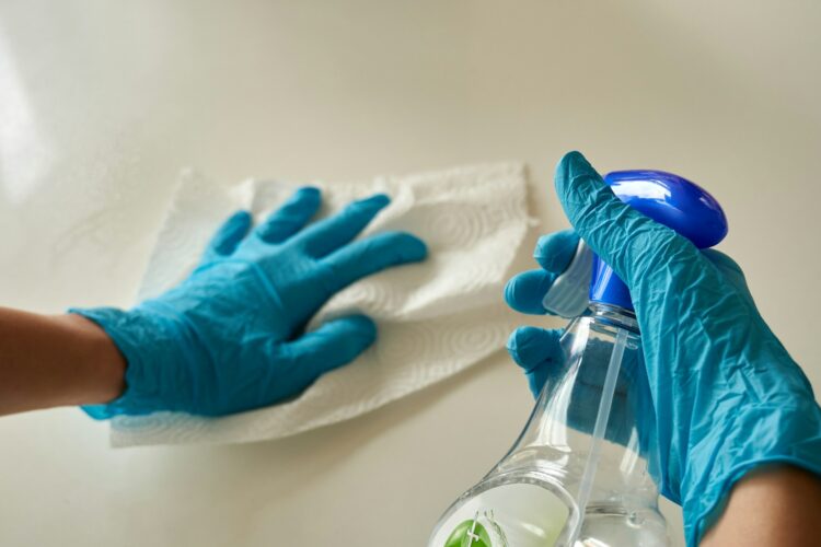 blue gloved hands holding cleaning products - dental infection control