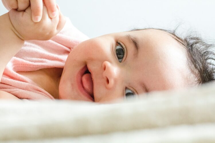 baby laying down with big smile - brushing baby teeth