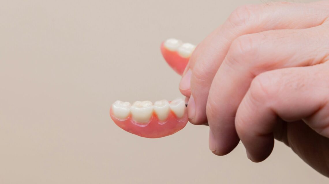 hand holding denture - when to replace dentures