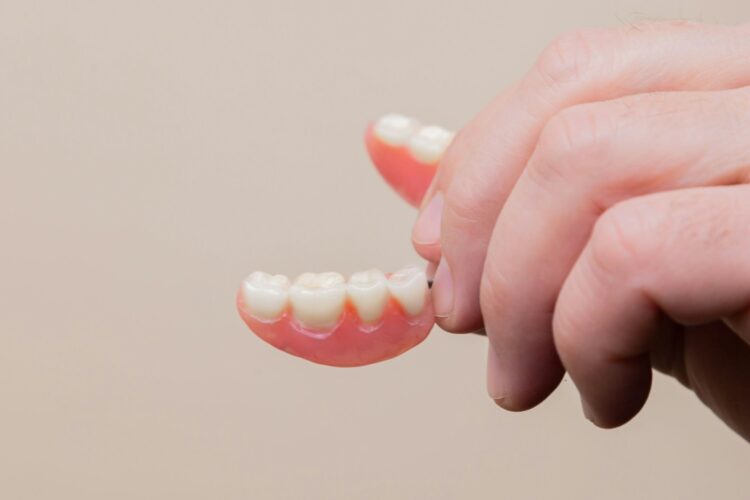 hand holding denture - when to replace dentures